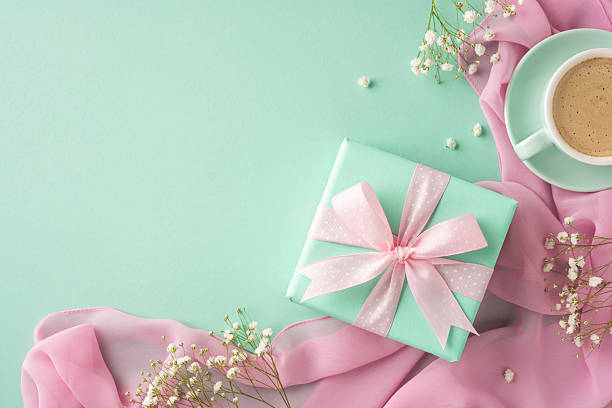 Gift box adorned with a ribbon accompanied by a coffee cup on a pastel surface, a delightful composition symbolizing special celebrations and thoughtful moments