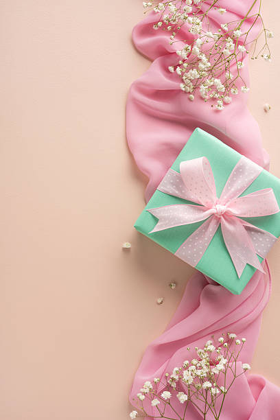 istock Elegant pastel-themed image featuring a wrapped gift box, pink fabric, and delicate flowers 2208807183