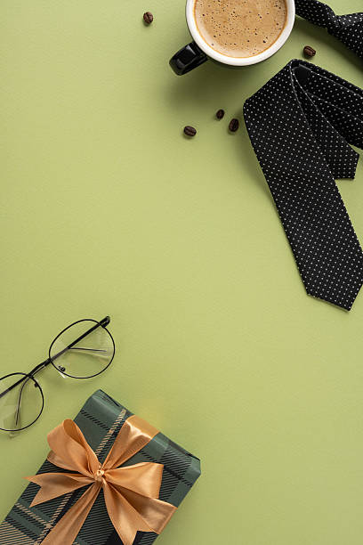 istock Flat lay of Father's Day vertical essentials featuring a gift box, tie, cup of coffee, and eyeglasses on a green background, conveying celebration and appreciation 2208807190