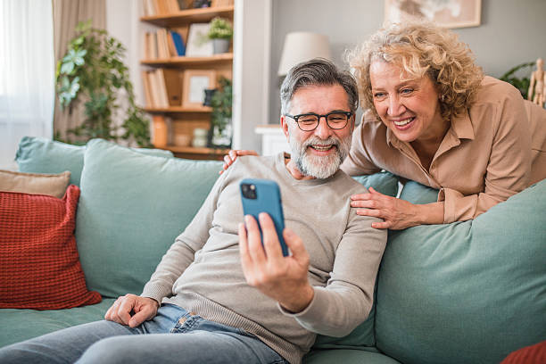 istock A senior man and a woman are having crazy fun using a smartphone at home 2208810214