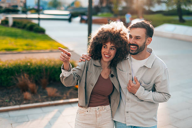 istock Happy couple walking and pointing while sightseeing in the city during sunset 2208810421