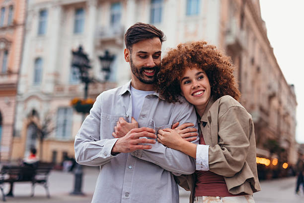 istock Young couple hugging in a city center square 2208810540