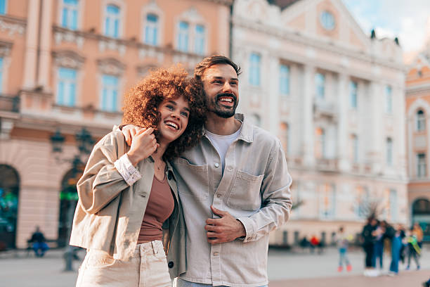 Happy couple embracing and smiling while sightseeing in a city