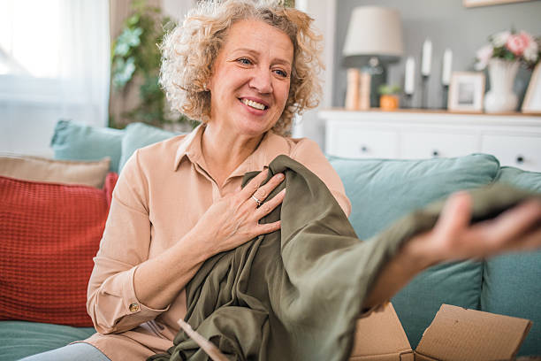 istock A smiling woman opens the package she ordered online, delighted with the wardrobe that arrived 2208811022