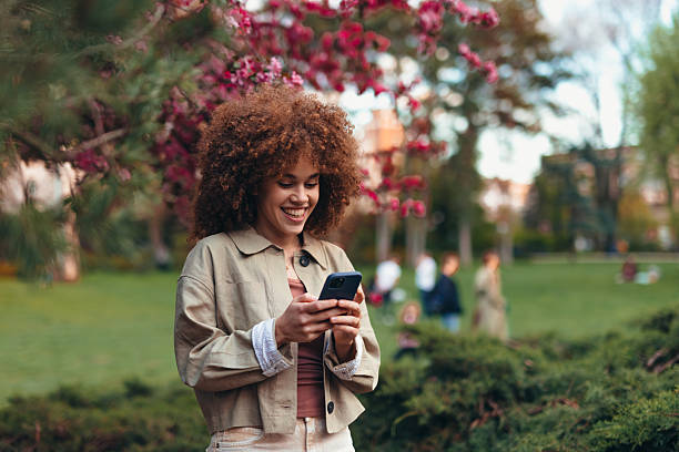 istock Young woman using smartphone in a park during spring 2208811147