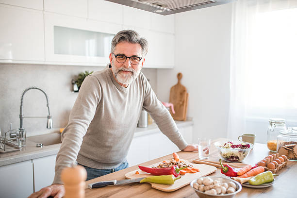 istock Carefree mature man looking directly at the camera while standing at the kitchen counter 2208811398