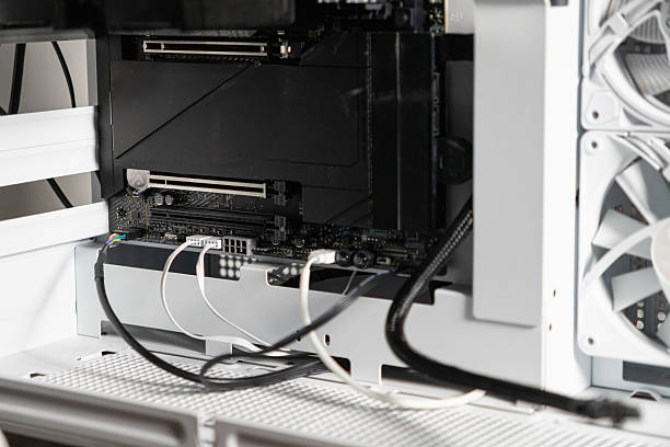 istock Close-up view of a PC motherboard inside a white computer case, showing open PCIe slots and connected power supply cables, prepared for GPU installation or upgrade 2208814386