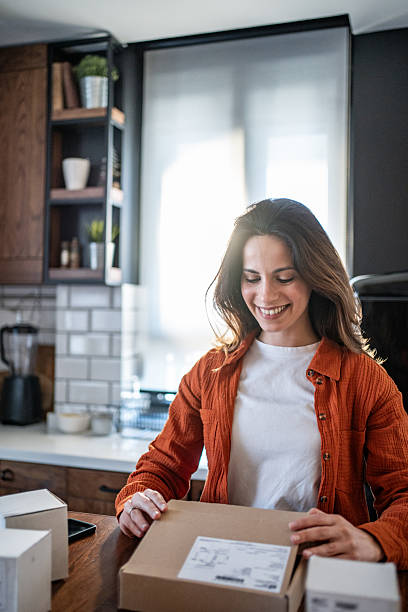 istock Young woman opening a package in her kitchen 2208822586