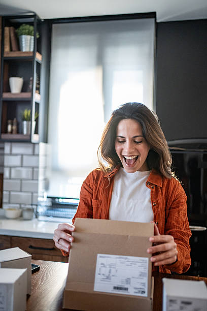 istock Excited woman opening a package in her kitchen 2208822605