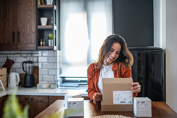 istock Happy woman opening a package in her modern kitchen 2208822623