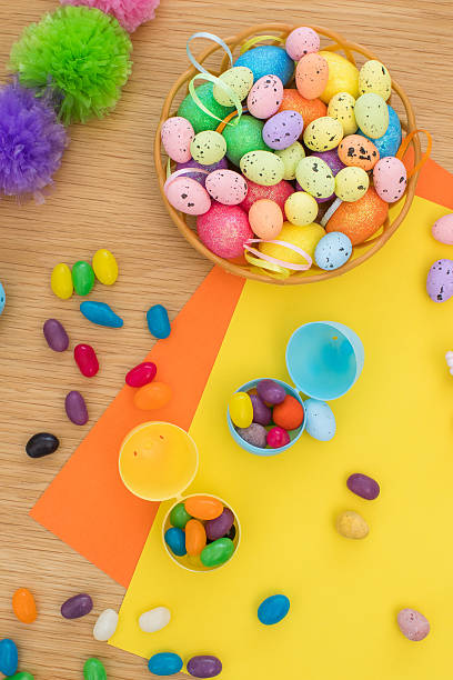 istock Bright background with candies in the form of Easter eggs in plastic eggs. Egg hunt concept. Happy Easter. Top view. 2208822775