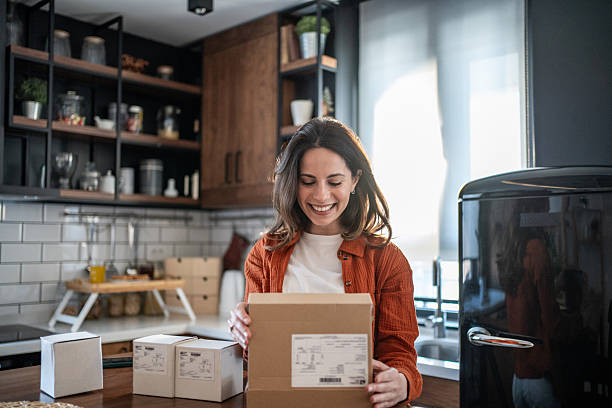 istock Happy woman unboxing parcel at home in her kitchen 2208822847