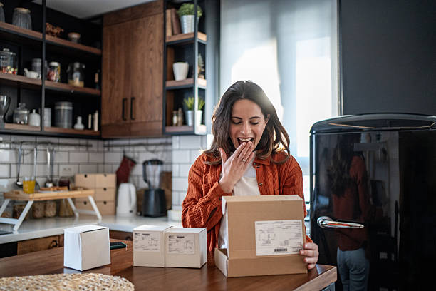 istock Excited woman opening a package in her kitchen 2208822853