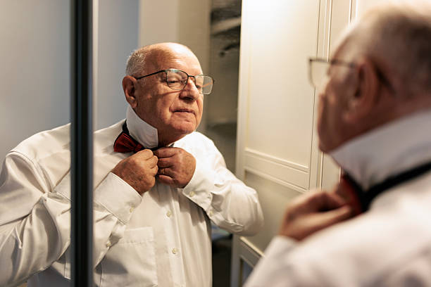 istock Senior man preparing for a family celebration, adjusting a red bow tie 2208823680