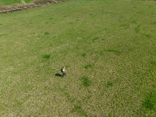 Adult man with backpack relaxing walk on springtime green grass meadow in countryside