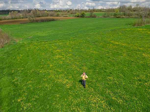 Adult man with backpack relaxing walk on springtime green grass meadow in countryside