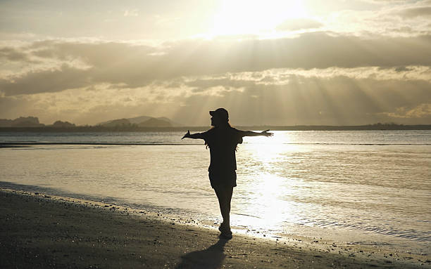 istock Silhouette of a woman open arms while strolling on the beach 2208831139