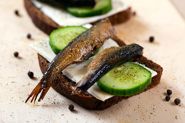 istock Sandwich black bread with sprats, cheese, cucumber and herbs. Snack for vodka 2208836413