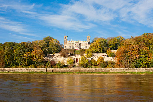 Aerial view of Dresden's historic architecture and lush green parks along the Elbe River on a sunny day.