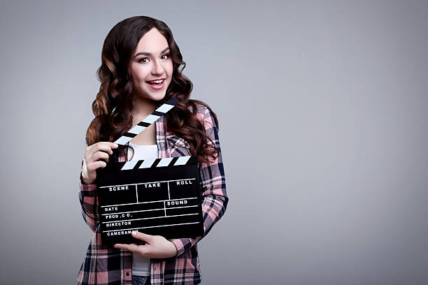 istock Young woman with clapper board on grey background 2208843589