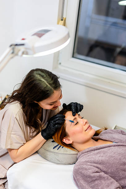 istock Beauty professional applying eyebrow tint to a woman's brows using a fine brush. 2208844015
