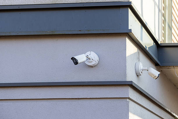 Security cameras mounted on modern building facade for surveillance and monitoring under daylight conditions