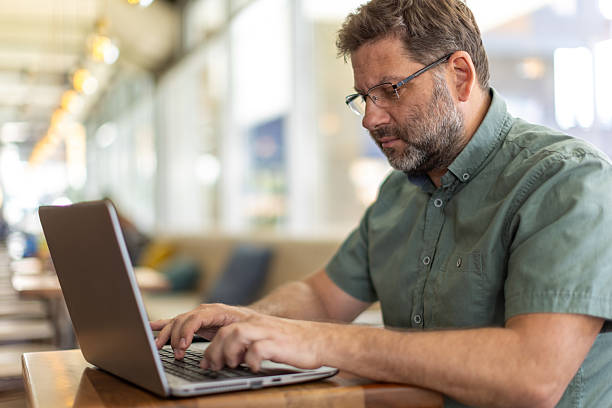 istock Mature man in cafe using laptop 2208844563