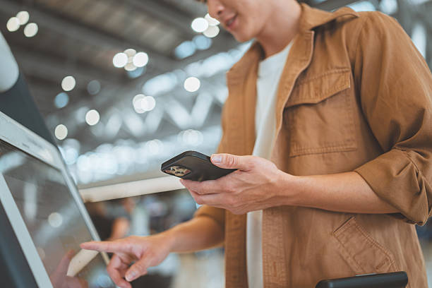 istock Closeup - Hands of man holding smartphone while using self check-in machine at the airport terminal getting the boarding pass, Technology in airport, Tourist journey trip concept 2208845971