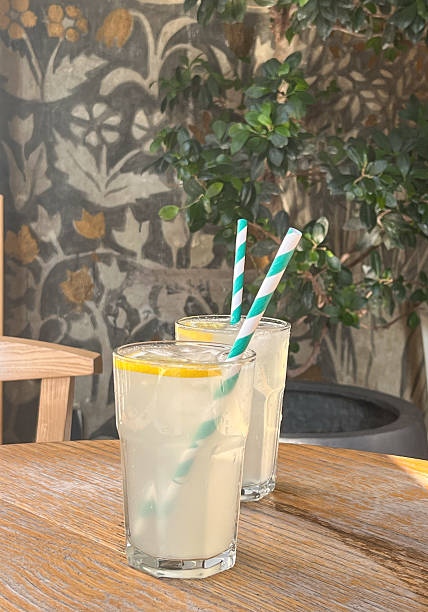 istock Mojito cocktail with fresh lemon and ice. Two glasses with refreshing citrus lemonade drink on wooden table in cafe. 2208850814