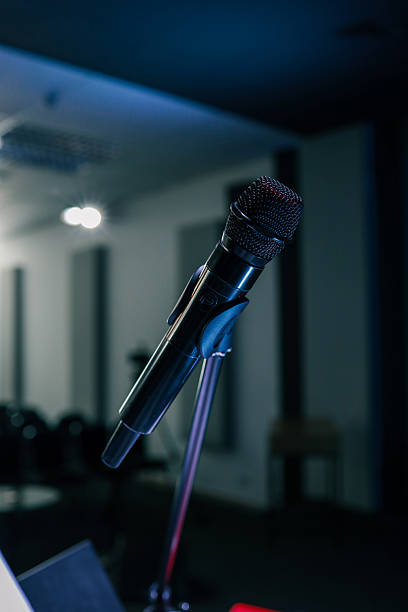 istock Professional black microphone on a stand in a dimly lit auditorium, prepared for a performance, speech, or recording 2208858532