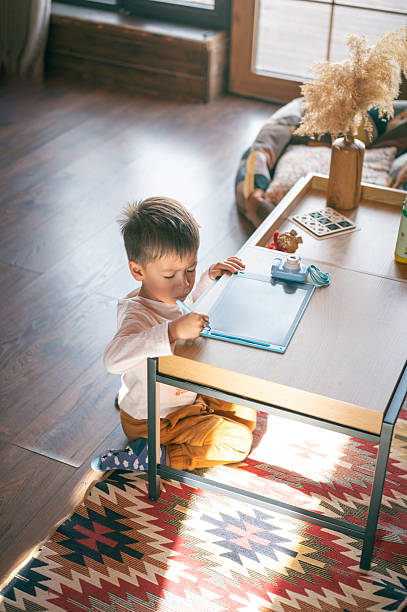 istock Young Boy Drawing on Digital Tablet in Cozy Log Cabin 2208862097