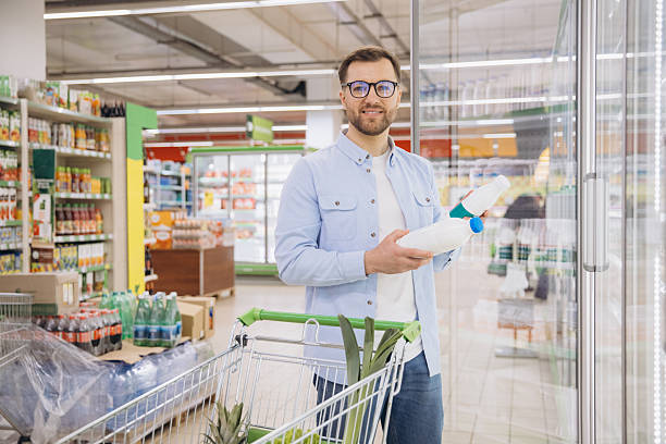 istock Smiling Customer Choosing Milk Bottles in Supermarket Refrigerator 2208865050