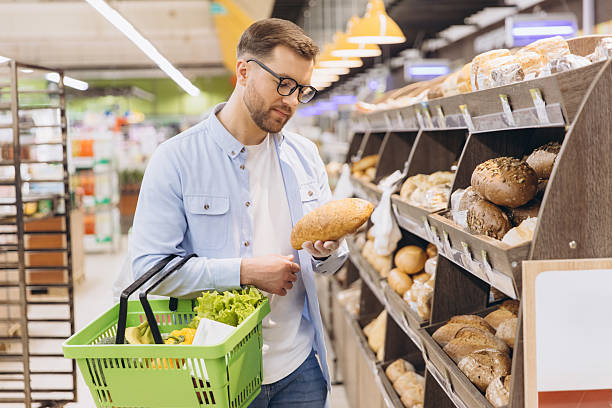 istock Man choosing bread in supermarket bakery section holding shopping basket 2208866241