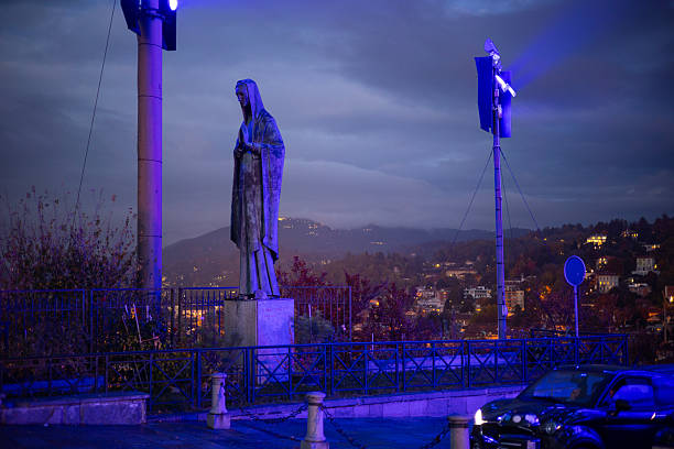Turin, Italy - Nov 08 2021: The Madonna dei Lavoratori statue illuminated at night with the city skyline in the background