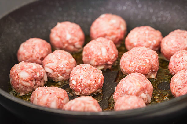 istock Uncooked meatballs start to sizzle in a hot pan. 2208876834