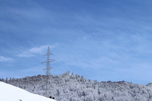 A snowy hill with power lines. Outdoor. Sky. Snow. Slope. Hill