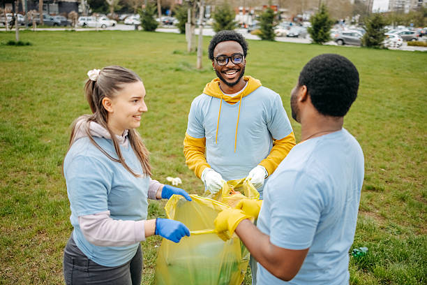 istock Group of young adults having fun doing community work together and having fun collecting garbage in public park 2208890185