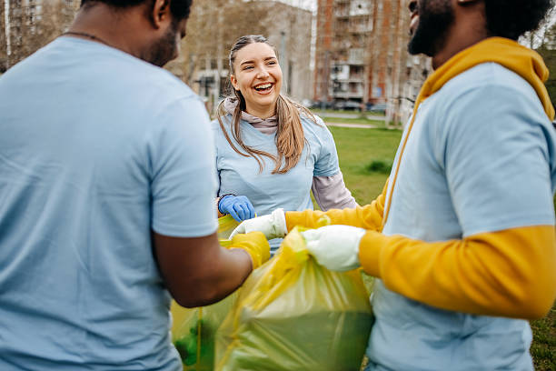 istock Group of young adults having fun doing community work together and having fun collecting garbage in public park 2208890208