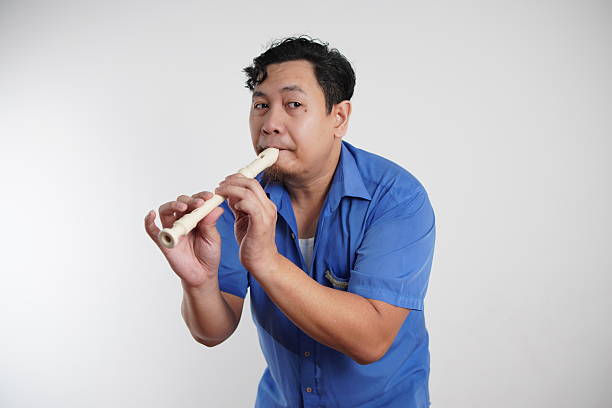 Young adult Asian man playing recorder flute, musical instrument