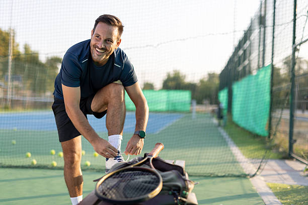 istock Man smiles while tying sneakers on the court before playing 2208898556
