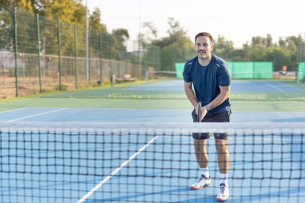 istock Man in action on tennis court with focused expression playing 2208898612
