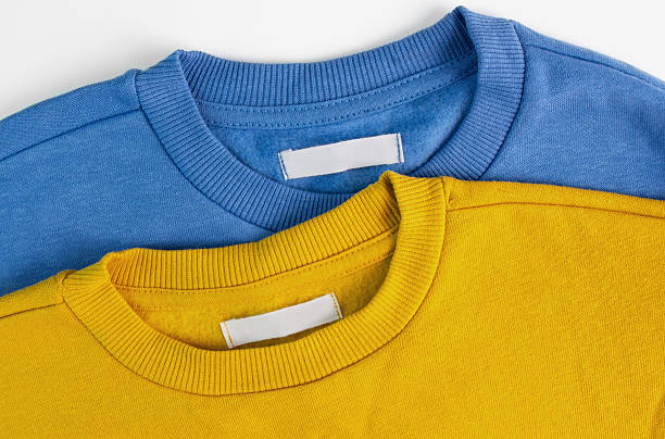 istock Blank clothing labels on yellow and blue sweater. Textile background 2208910537
