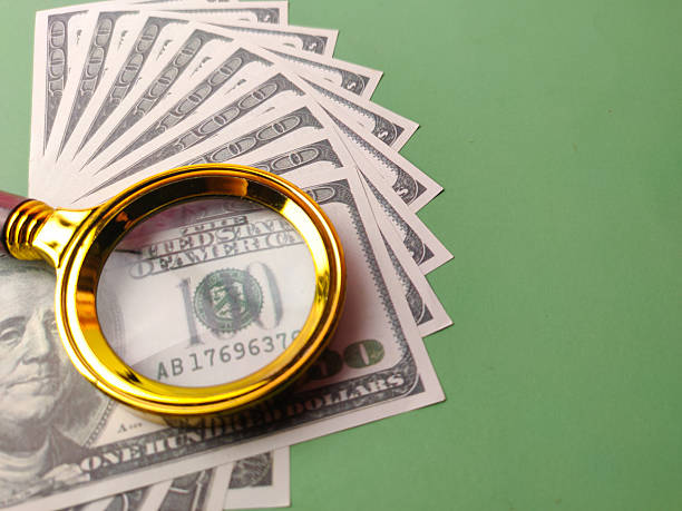 istock Closeup gold magnifying glass on a one hundred dollars 2208912933