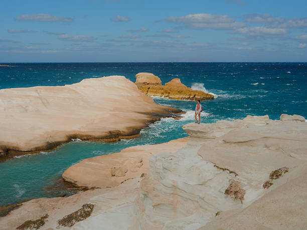 Woman exploring white cliffs on Sarakiniko beach on Milos island during island hopping trip in  Greece