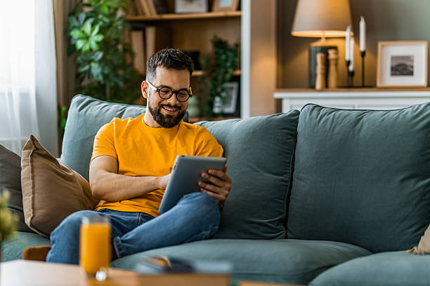 Man relaxing at home and using digital tablet at home.