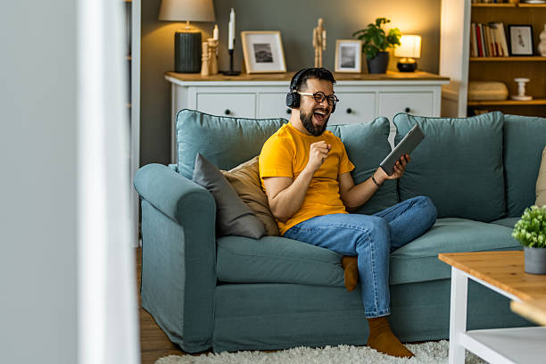 istock Man singing to music on headphones while using digital tablet at home. 2208918664
