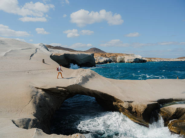 Woman exploring white cliffs on Sarakiniko beach on Milos island during island hopping trip in  Greece