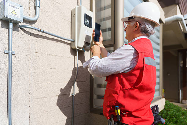 Experienced Latin American electrician photographing an electrical meter with his smartphone.