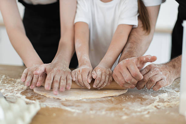 istock Family cooking together in the kitchen rolling dough with a rolling pin 2208927782