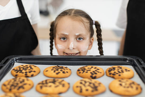 istock Young girl with cookies on baking tray smiling in kitchen setting 2208927801